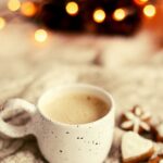 Warm beleuchtetes Wohnzimmer mit Kerzen, Decke und Tasse Tee als Symbol für hyggelige, leise Feiertage