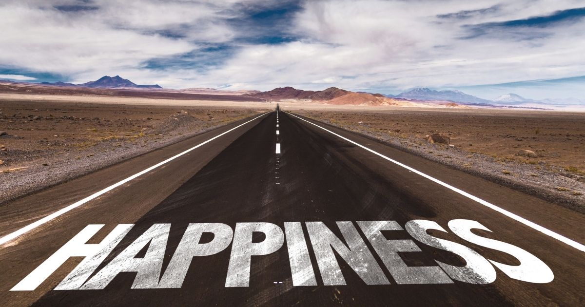 Wüstenstraße in die Ferne mit dem Wort „HAPPINESS“ – Start in Dein Glück.